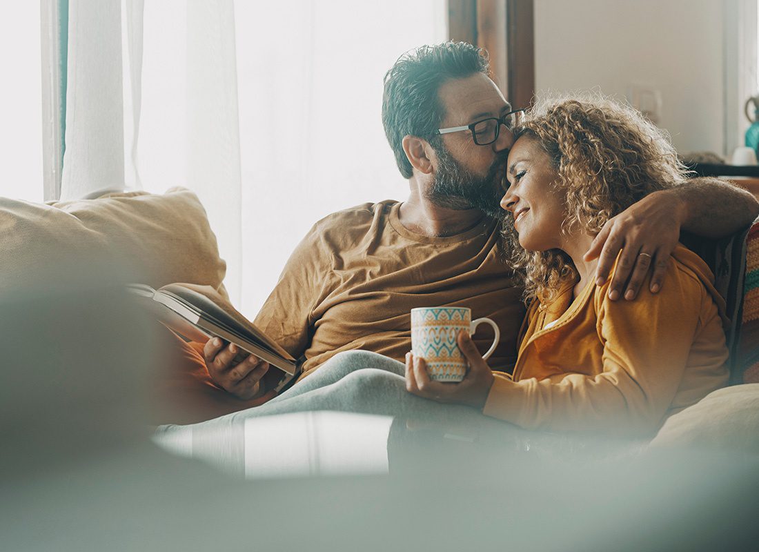 We Are Independent - Portrait of a Cheerful Middle Aged Couple Enjoying Spending Time Together Reading and Drinking Coffee While Sitting on the Sofa